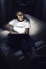 Молода афроамериканська жінка дивиться онлайн tv вночі, використовуючи ноутбук. — стокове фото