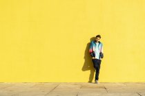 Mann lehnt mit Händen in Taschen an gelber Wand — Stockfoto