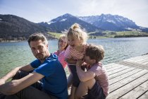 Austria, Tirolo, Walchsee, famiglia felice seduta su un molo sul lungolago — Foto stock
