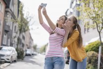 Novias tomando selfie en ciudad soleada - foto de stock