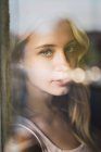 Ritratto di giovane donna dietro il vetro della finestra — Foto stock