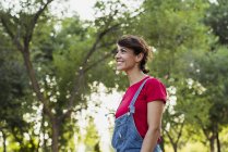Smiling woman in denim jumpsuit relaxing in nature — Stock Photo