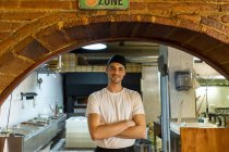 Retrato de padeiro de pizza confiante em pé na cozinha — Fotografia de Stock