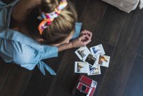 Young woman lying on floor looking at instant photos — Stock Photo