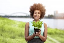 Porträt einer lächelnden Frau, die Pflanzen im Freien hält — Stockfoto