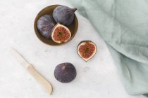 Sliced and whole fresh figs, kitchen knife and cloth — Stock Photo