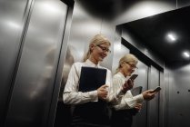 Donna d'affari che controlla il cellulare in ascensore — Foto stock