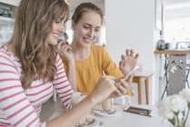 Zwei Freundinnen treffen sich mit Smartphone im Café — Stockfoto