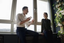 Geschäftsmann und Geschäftsfrau im Gespräch am Fenster — Stockfoto