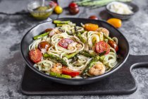 Spaghetti with shrimps, green asparagus, tomatoes, pesto and parmesan — Stock Photo