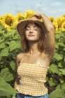 Junge Frau mit Strohhut auf dem Kopf in einem Sonnenblumenfeld — Stockfoto