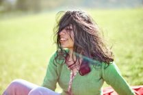Glückliche junge Frau mit wehenden Haaren auf einer Wiese — Stockfoto
