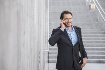 Homme d'affaires souriant dans les escaliers parlant sur smartphone — Photo de stock