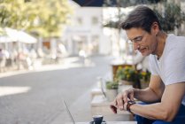 Reifer Geschäftsmann sitzt im Café und kontrolliert die Uhrzeit — Stockfoto