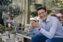 Mature businessman sitting in coffee shop, drinking coffee — Stock Photo