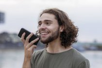 Молодий чоловік використовує смартфон на березі річки — стокове фото
