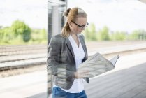 Reife Geschäftsfrau wartet am Bahnsteig und liest Zeitung — Stockfoto