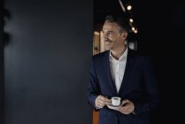 Lächelnder Geschäftsmann mit Espressotasse, der zur Seite schaut — Stockfoto
