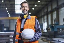 Retrato del hombre sonriente usando ropa de trabajo protectora en fábrica - foto de stock