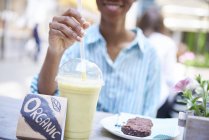 Жінка п'є органічну смужку в тротуарному кафе, частковий вид — стокове фото