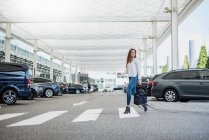 Young woman with bag crossing street at zebra crossing — Stock Photo