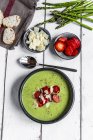 Green asparagus cream soup with strawberry, parmesan and baguette — Stock Photo