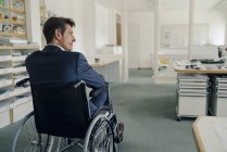 Hombre de negocios discapacitado sentado en silla de ruedas - foto de stock