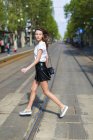 Jovem mulher cruzando rua com trilhos de bonde na cidade — Fotografia de Stock
