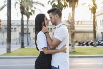 Молодая романтическая пара целуется на размытом фоне города — стоковое фото