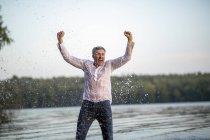 Screaming wet mature man standing at lake — Stock Photo