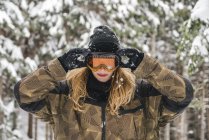 Junge Frau setzt Skibrille im Winterwald auf — Stockfoto
