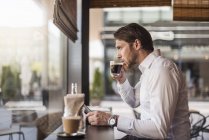 Бізнесмен з планшетом в кафе, що п'є каву зі скла — стокове фото
