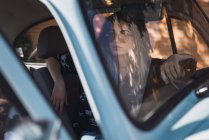 Junge Frau trägt Sonnenbrille und sitzt im Auto — Stockfoto