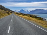 Nuova Zelanda, Isola del Sud, strada vuota con Aoraki Mount Cook e Lago Pukaki sullo sfondo — Foto stock