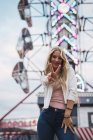 Lächelnde blonde junge Frau blickt in die Kamera und gestikuliert mit den Fingern Frieden — Stockfoto