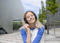 Mujer rubia joven con auriculares - foto de stock