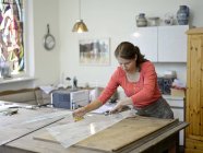 Mujer trabajando sobre cristal en taller de vidriera - foto de stock