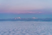 Vol au-dessus des nuages avec des montagnes en arrière-plan — Photo de stock