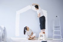 Couple painting house shape on wall in new apartment — Stock Photo