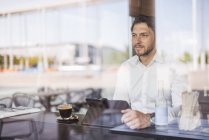 Бизнесмен за окном с планшетом в кафе — стоковое фото