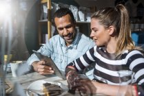 Young woman and man sharing tablet in a cafe — Stock Photo