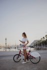 Модні молоді жінки вивчають Барселону з велосипедом, використовуючи смартфон — стокове фото