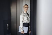 Confident businesswoman in office holding laptop — Stock Photo