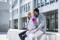 Active couple with water bottle having a break in the city — Stock Photo