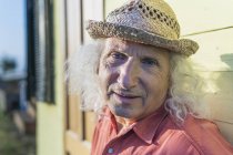 Retrato de homem sênior com cabelos longos e grisalhos usando chapéu de palha — Fotografia de Stock