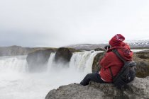 Island, nördlich von Island, junger Mann fotografiert Wasserfall — Stockfoto