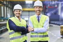 Portrait of smiling managers wearing protective workwear in factory — Stock Photo