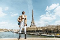Франция, Париж, Смолящая женщина на мосту с Эйфелевой башней на заднем плане — стоковое фото