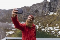 Islanda, uomo barbuto sorridente con smartphone, selfie — Foto stock