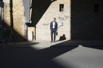 Бизнесмен, стоящий у стены граффити и оглядывающийся вокруг — стоковое фото
